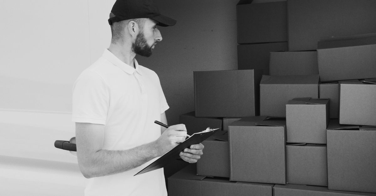 A delivery man inspecting cardboard boxes in a van, preparing for shipment.